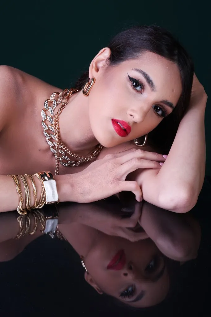 Model looking to camera, arms folded on the black mirror