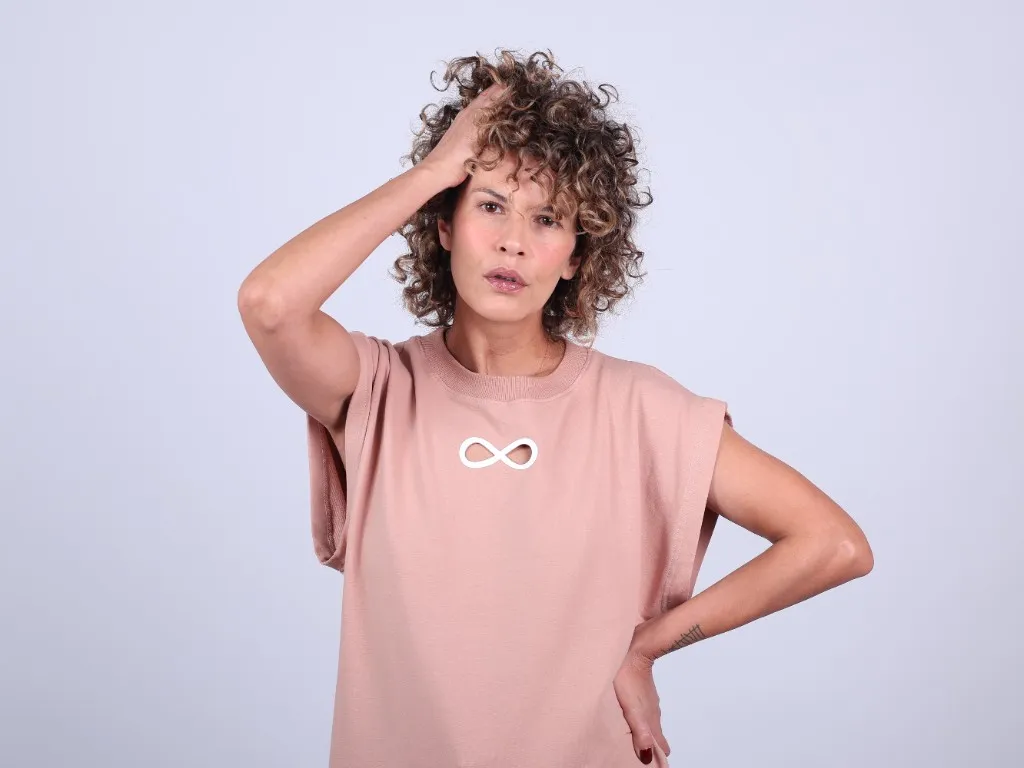 A hand pushed into her hair, the other at her hip, distress across her face