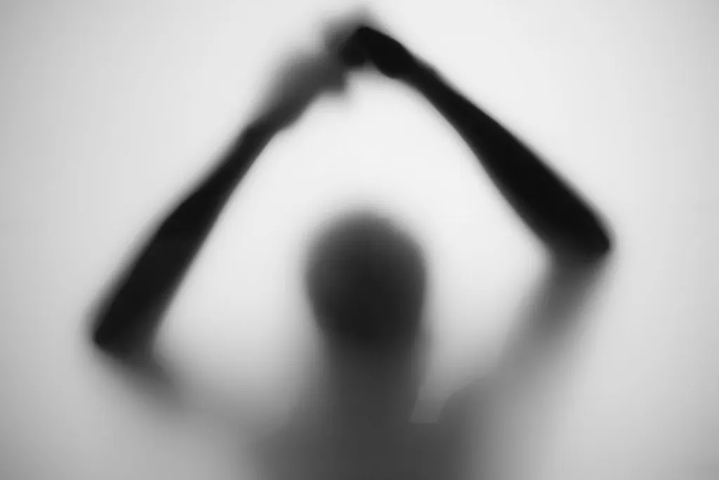Blurred silhouette behind frosted glass, arms raised into a triangle