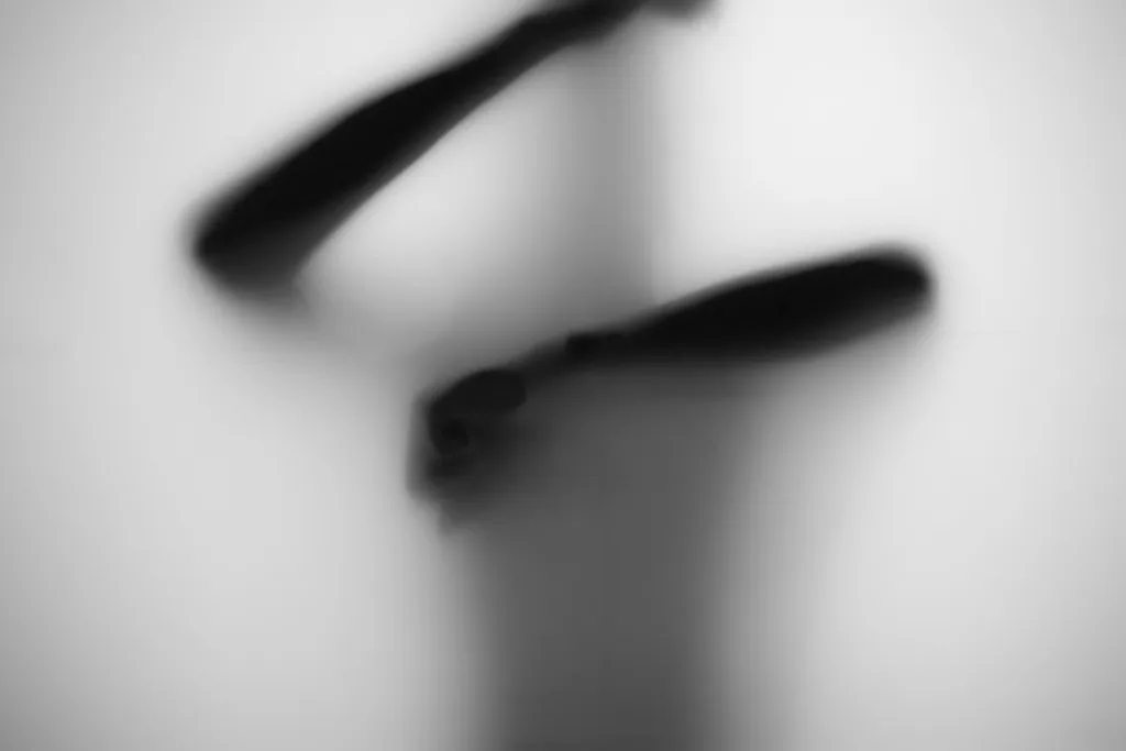 Abstract dark limbs pressed against frosted glass