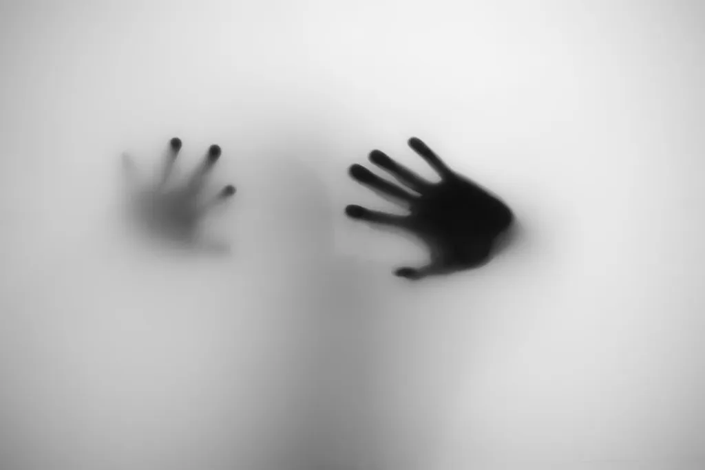 Two hands pressed flat against the frosted glass