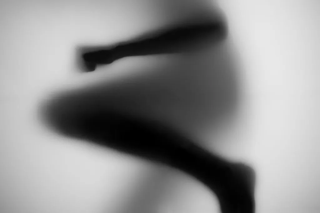 Bent legs forming an abstract dark shape behind glass