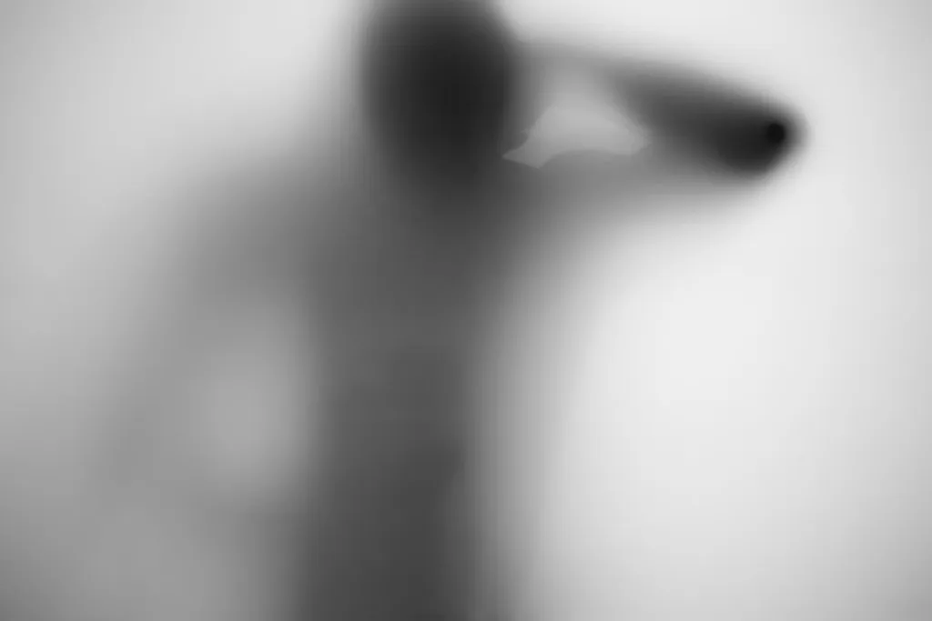 A figure leaning, shoulder and head pressed toward the glass
